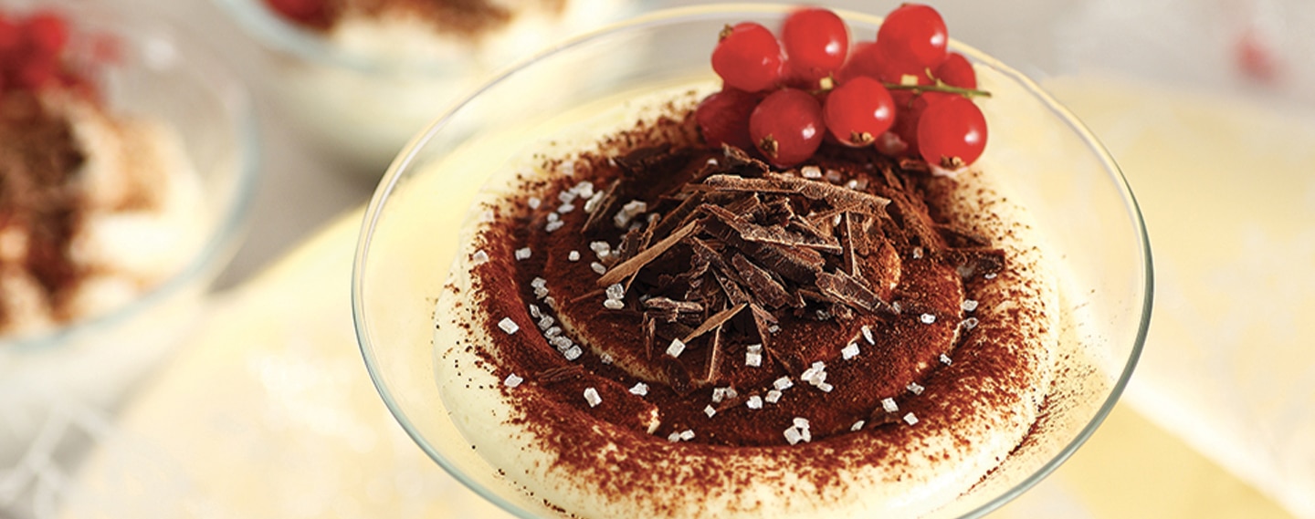 Tiramisù fatto in casa in un bicchiere guarnito con ribes