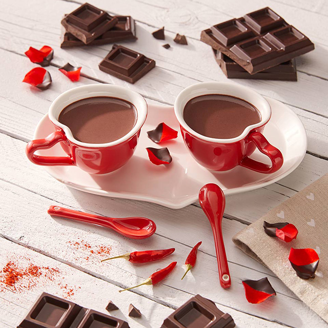 Due budini al cioccolato in tazze rosse a forma di cuore