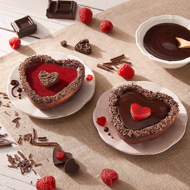 Due crostatine a forma di cuore con cioccolato e lamponi